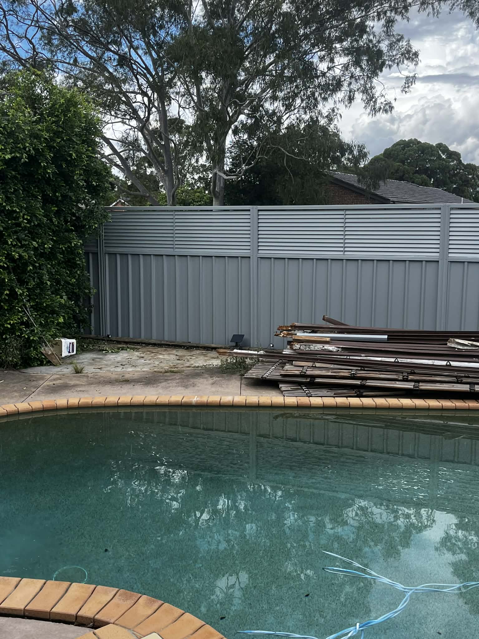 Grey Colorbond fence with a louvre extension beside a pool